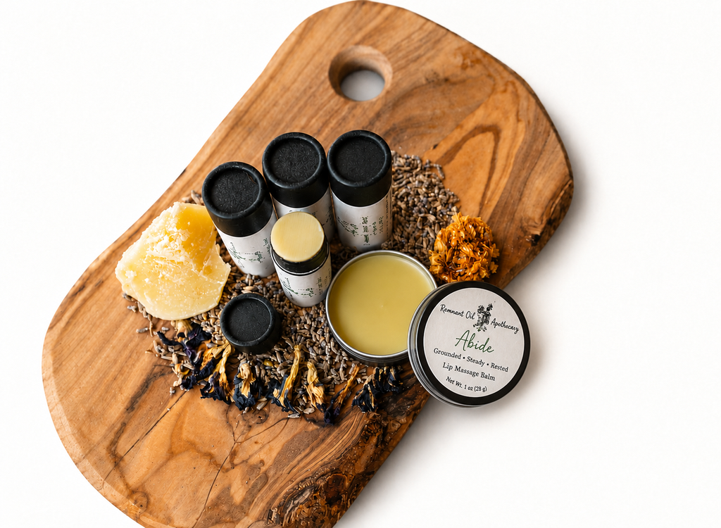 Abide lip balm tubes and labeled tin arranged with dried botanicals on a rustic wooden board.